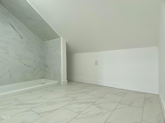 bathroom featuring lofted ceiling and tiled shower