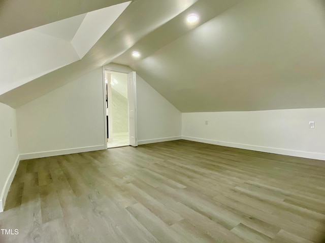 additional living space with light hardwood / wood-style floors and lofted ceiling