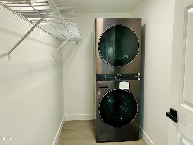 washroom with stacked washer and dryer and light hardwood / wood-style floors