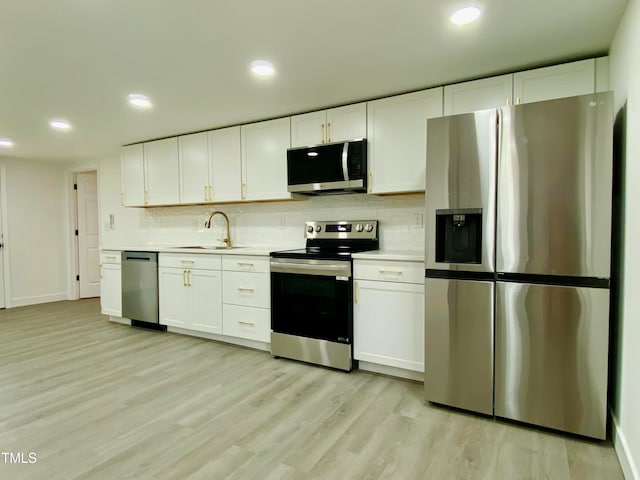 kitchen with backsplash, sink, appliances with stainless steel finishes, light hardwood / wood-style floors, and white cabinetry