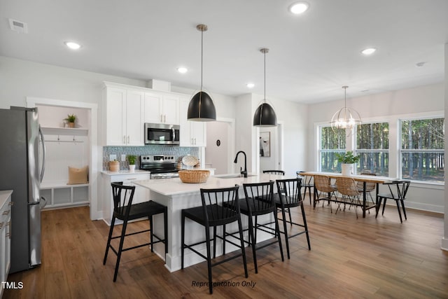 kitchen featuring dark wood-type flooring, appliances with stainless steel finishes, a kitchen island with sink, and white cabinets