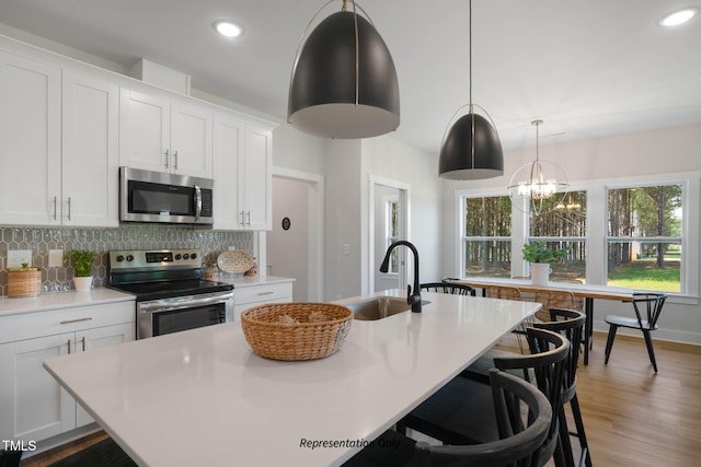 kitchen featuring a center island with sink, sink, white cabinetry, and stainless steel appliances