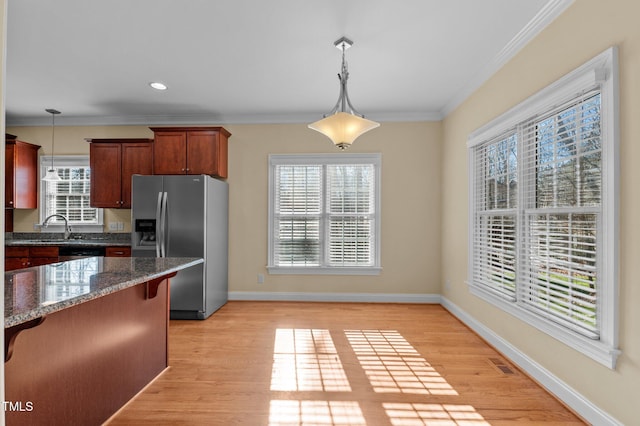 kitchen featuring pendant lighting, light wood-type flooring, stainless steel appliances, and ornamental molding