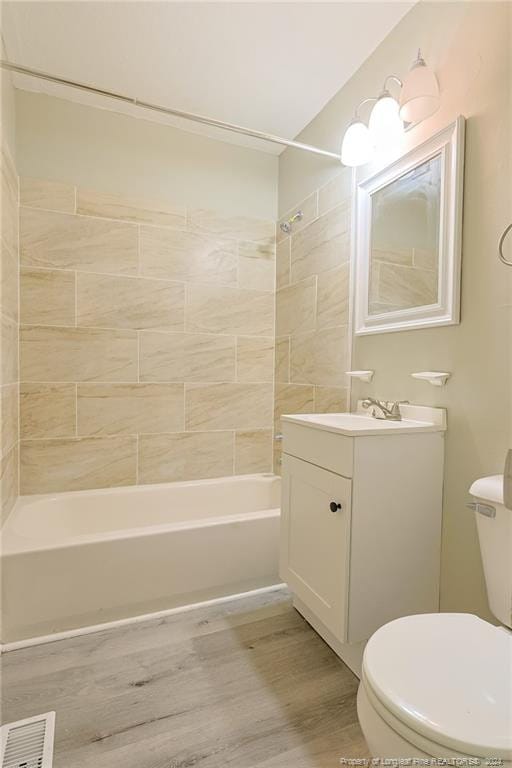 full bathroom with vanity, toilet, hardwood / wood-style flooring, and tiled shower / bath combo