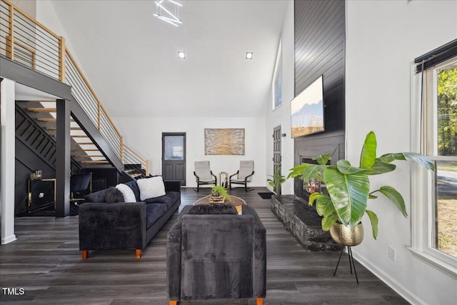 living room featuring high vaulted ceiling, dark hardwood / wood-style flooring, a healthy amount of sunlight, and a fireplace