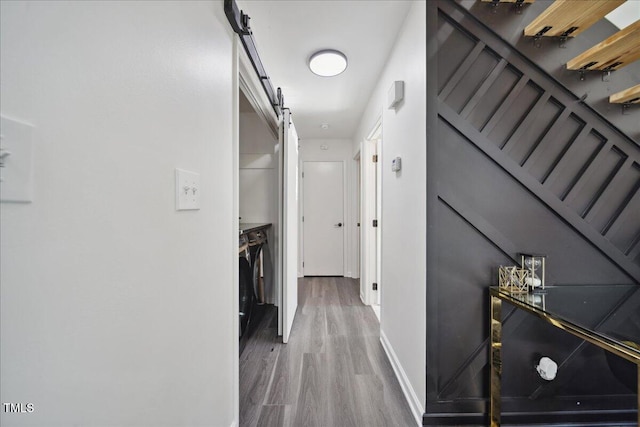 hallway with a barn door and hardwood / wood-style flooring