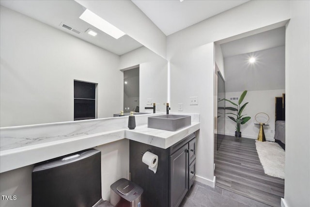 bathroom with hardwood / wood-style floors, vanity, and a skylight