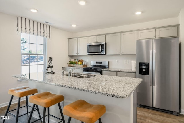 kitchen featuring light stone countertops, hardwood / wood-style flooring, gray cabinetry, and appliances with stainless steel finishes