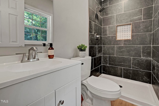 bathroom with vanity, toilet, tiled shower, and hardwood / wood-style floors