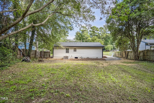 back of property with central air condition unit and a lawn