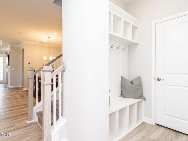 mudroom featuring light hardwood / wood-style floors, an inviting chandelier, and ornamental molding