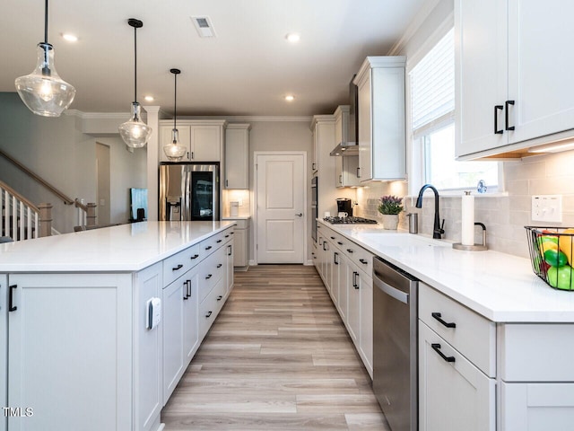 kitchen with white cabinets, appliances with stainless steel finishes, sink, pendant lighting, and a center island