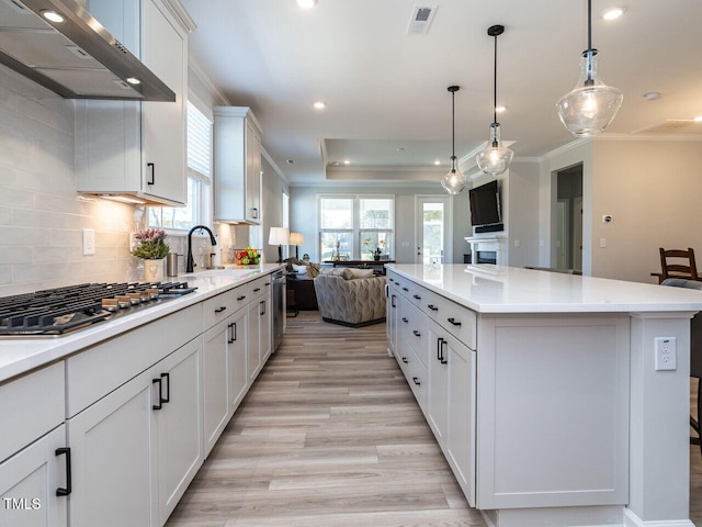 kitchen with a large island, stainless steel gas stovetop, white cabinets, and plenty of natural light