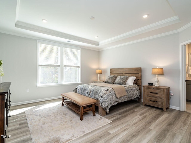 bedroom with ornamental molding, a tray ceiling, and light wood-type flooring