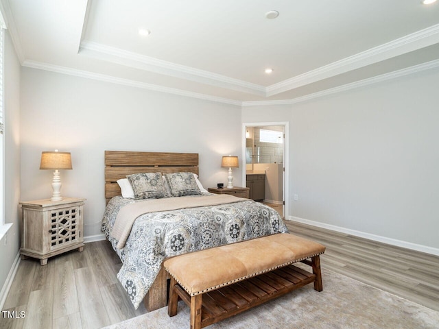 bedroom featuring ensuite bath, a raised ceiling, ornamental molding, and light hardwood / wood-style flooring