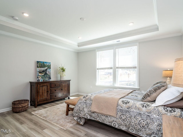 bedroom with crown molding, light hardwood / wood-style flooring, and a tray ceiling