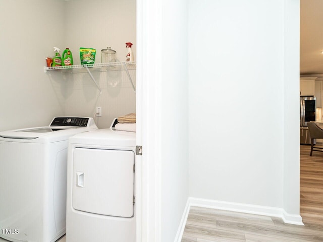 clothes washing area featuring washer and clothes dryer and light wood-type flooring