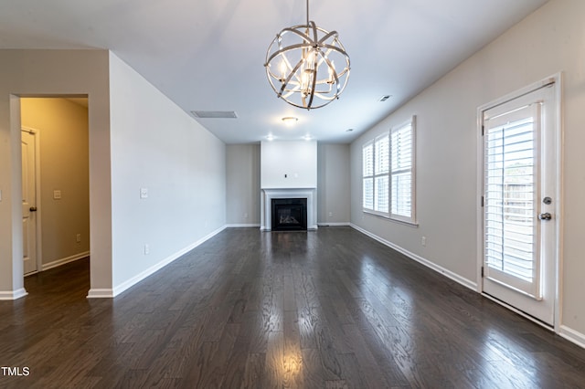 unfurnished living room featuring an inviting chandelier and dark wood-type flooring