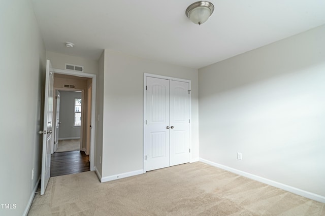 unfurnished bedroom featuring light carpet and a closet