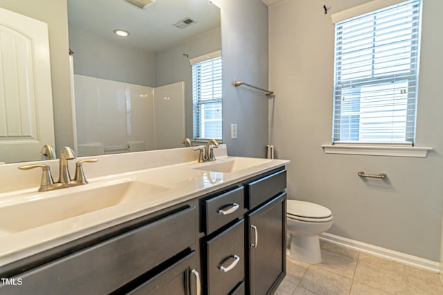 bathroom with tile patterned flooring, vanity, toilet, and a wealth of natural light