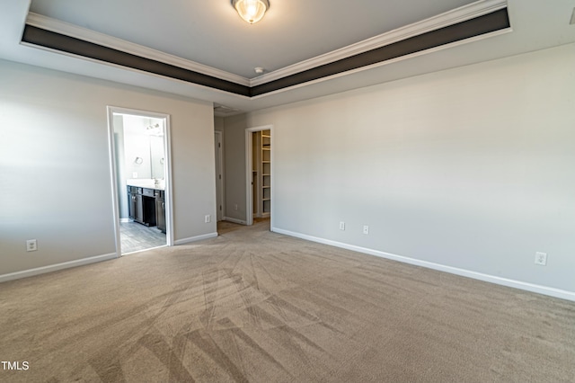 carpeted empty room featuring a raised ceiling and ornamental molding