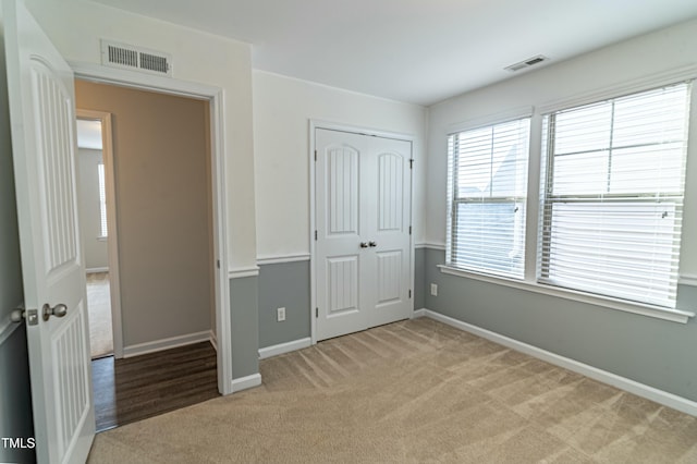 unfurnished bedroom featuring light colored carpet and a closet