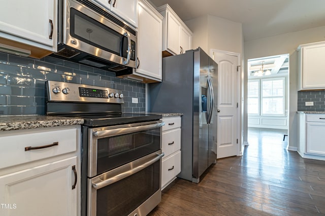 kitchen with white cabinets, appliances with stainless steel finishes, and light stone countertops