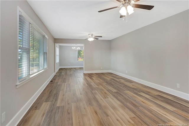 spare room featuring ceiling fan with notable chandelier and light hardwood / wood-style floors