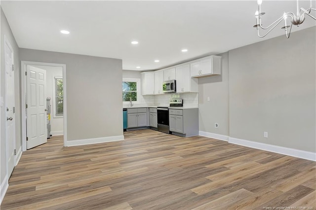 kitchen featuring decorative backsplash, appliances with stainless steel finishes, light wood-type flooring, and white cabinets