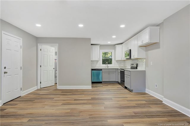 kitchen featuring sink, backsplash, appliances with stainless steel finishes, white cabinets, and light wood-type flooring