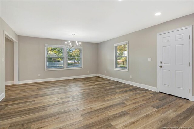 empty room featuring hardwood / wood-style flooring and a chandelier