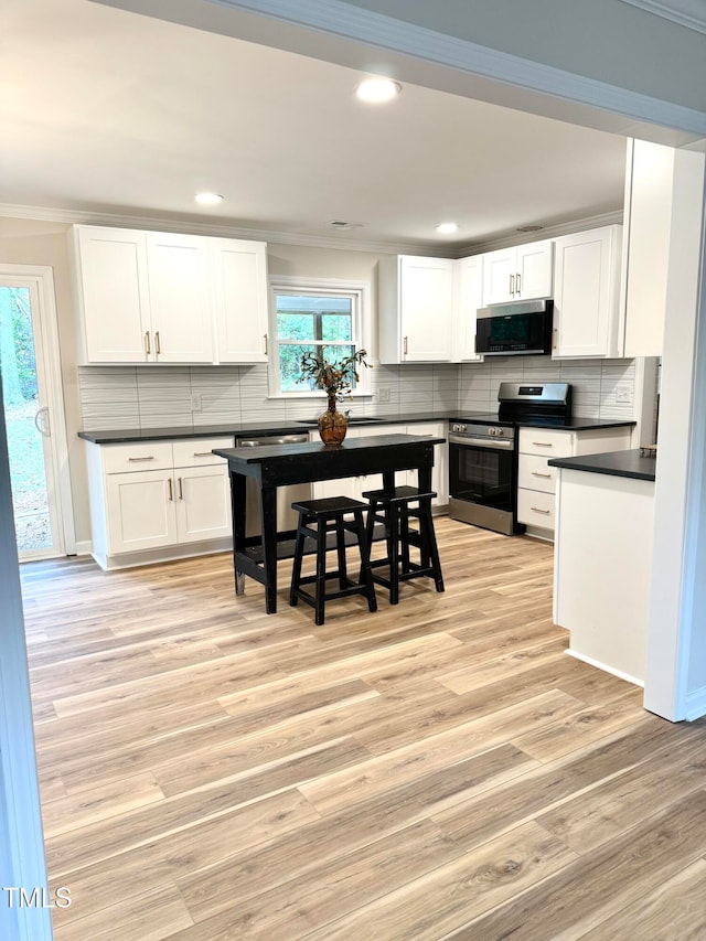 kitchen with stainless steel appliances, crown molding, light hardwood / wood-style flooring, white cabinetry, and plenty of natural light