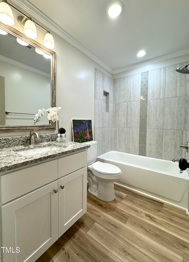 full bathroom with ornamental molding, vanity, hardwood / wood-style flooring, toilet, and tiled shower / bath