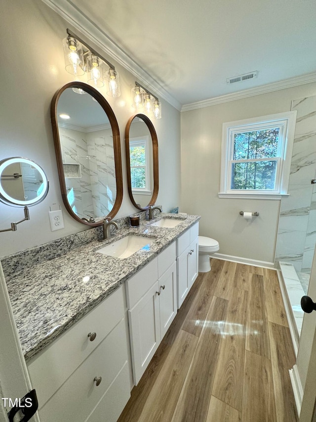 bathroom with a healthy amount of sunlight, vanity, ornamental molding, and hardwood / wood-style flooring