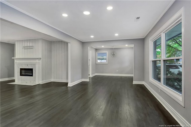 unfurnished living room with dark hardwood / wood-style floors, a premium fireplace, and a wealth of natural light