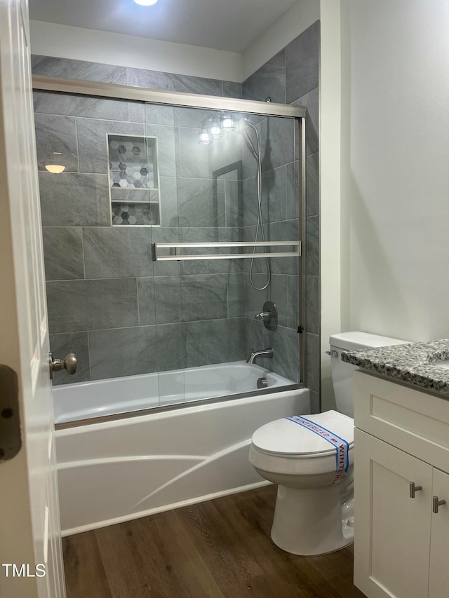 full bathroom with toilet, vanity, wood-type flooring, and shower / bath combination with glass door