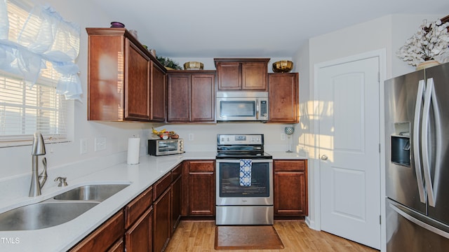 kitchen with sink, appliances with stainless steel finishes, and light hardwood / wood-style floors