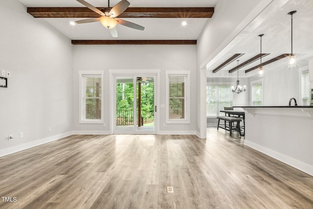 unfurnished living room with beamed ceiling, light wood-type flooring, and plenty of natural light