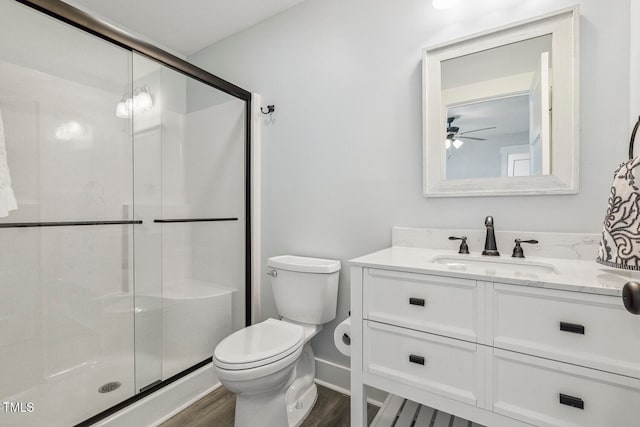 bathroom with walk in shower, vanity, hardwood / wood-style flooring, toilet, and ceiling fan