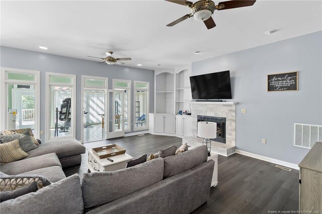 living room featuring ceiling fan, dark hardwood / wood-style flooring, and a tile fireplace