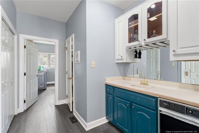 interior space with white cabinets, dishwashing machine, dark hardwood / wood-style floors, sink, and blue cabinets