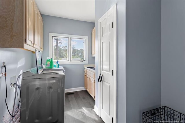 clothes washing area featuring independent washer and dryer, cabinets, and light wood-type flooring