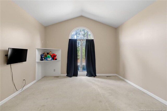 empty room with vaulted ceiling and light carpet