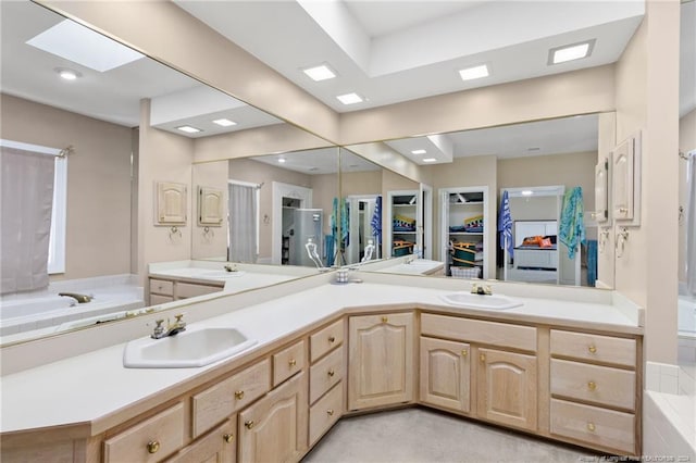 bathroom with vanity, a skylight, and separate shower and tub