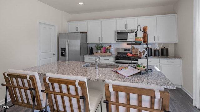 kitchen with stainless steel appliances, a center island with sink, sink, white cabinets, and dark hardwood / wood-style flooring