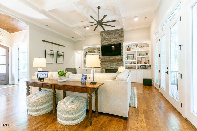 living room with coffered ceiling, a healthy amount of sunlight, light hardwood / wood-style flooring, and a fireplace