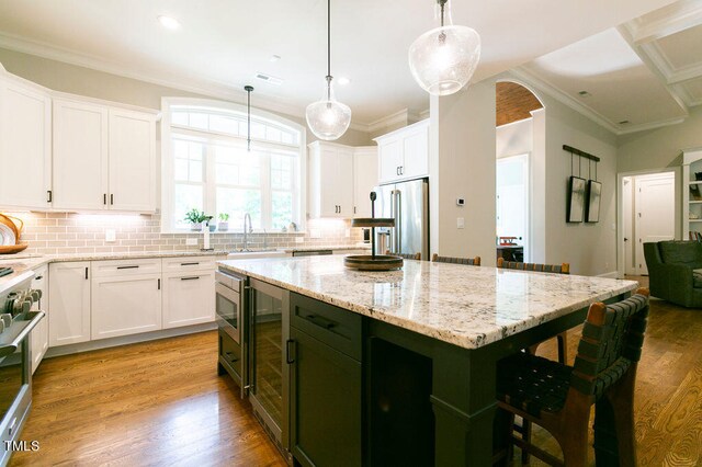 kitchen with a kitchen island, appliances with stainless steel finishes, wood-type flooring, and white cabinets