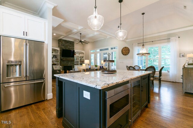 kitchen featuring a fireplace, a kitchen island, dark hardwood / wood-style flooring, hanging light fixtures, and stainless steel appliances