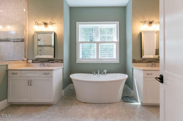 bathroom with backsplash, vanity, a tub, and tile patterned flooring