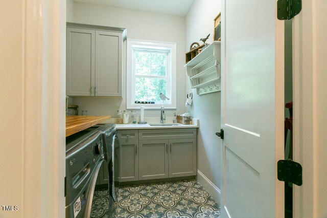 kitchen featuring gray cabinets, wood counters, sink, and washer and dryer